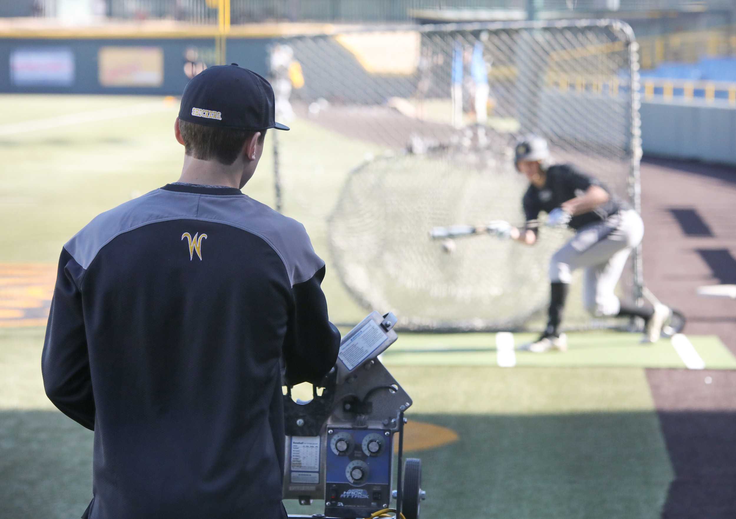 Wichita State baseball manager Nathan Brisco loads the pitching machine while a player takes bunting practice on Feb. 10, 2017. Brisco is a transfer student from Kansas City Community College where he redshirted on their baseball team as a freshman last year. Though a shoulder injury prevented Brisco from playing at KCCC, he has still found a way to be involved with baseball here at WSU.