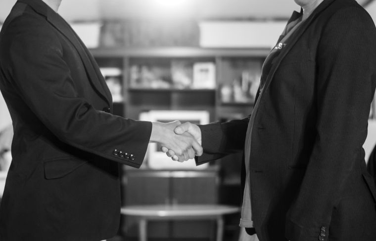 Two businesman shaking hands with confident postures after a meeting.