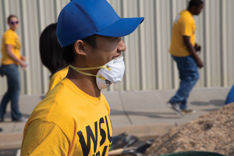 Wichita State junior Khun Min moves a wheelbarrel of mulch Saturday for the WSU Serves Moore campaign. Fifty students from WSU helped the citizens of Moore, Okla. with the rebuilding process after a tornado struck the town on May 20.