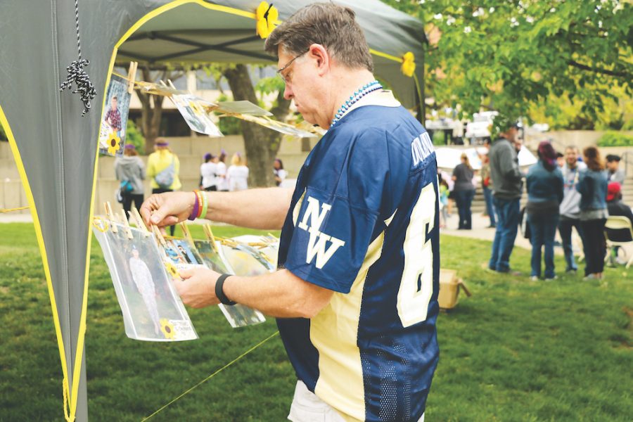 Richard Powell, an attendee at the Out of the Darkness event, hangs a picture of loved ones in memory before the walk. Powell and his wife, Karen, have participated in the walk for two years in support of loved ones who have committed suicide.