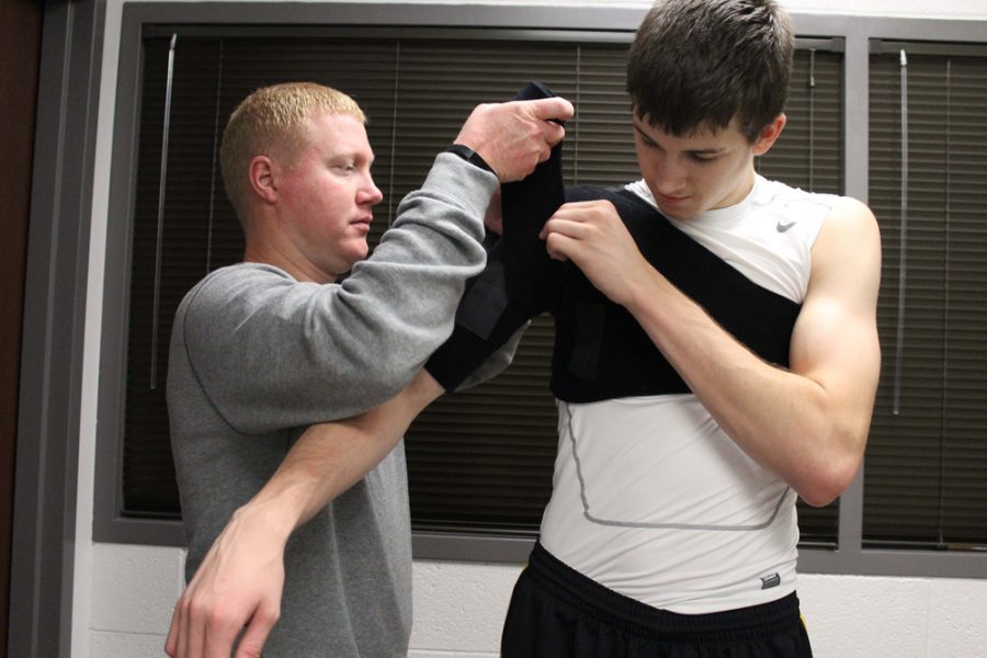 Assistant athletic trainer for men’s basketball, Todd Fagan (left), wrapping freshman player Austin Reeves’ arm and shoulder (right).