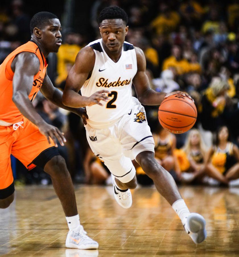 Junior guard Daishon Smith (2) drives to the paint against an OSU defender in the first half during the annual INSTRUST Bank Arena game Saturday evening. The Shockers fell to Oklahoma State by the score of 93-76.