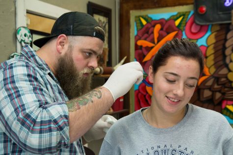 tattoo artist Austin Liebst shaves the area where Emma Hickey will be getting her second tattoo, at Artist at Large. Hickey's first tattoo is on her wrist and it's her mother's handwriting with the message: