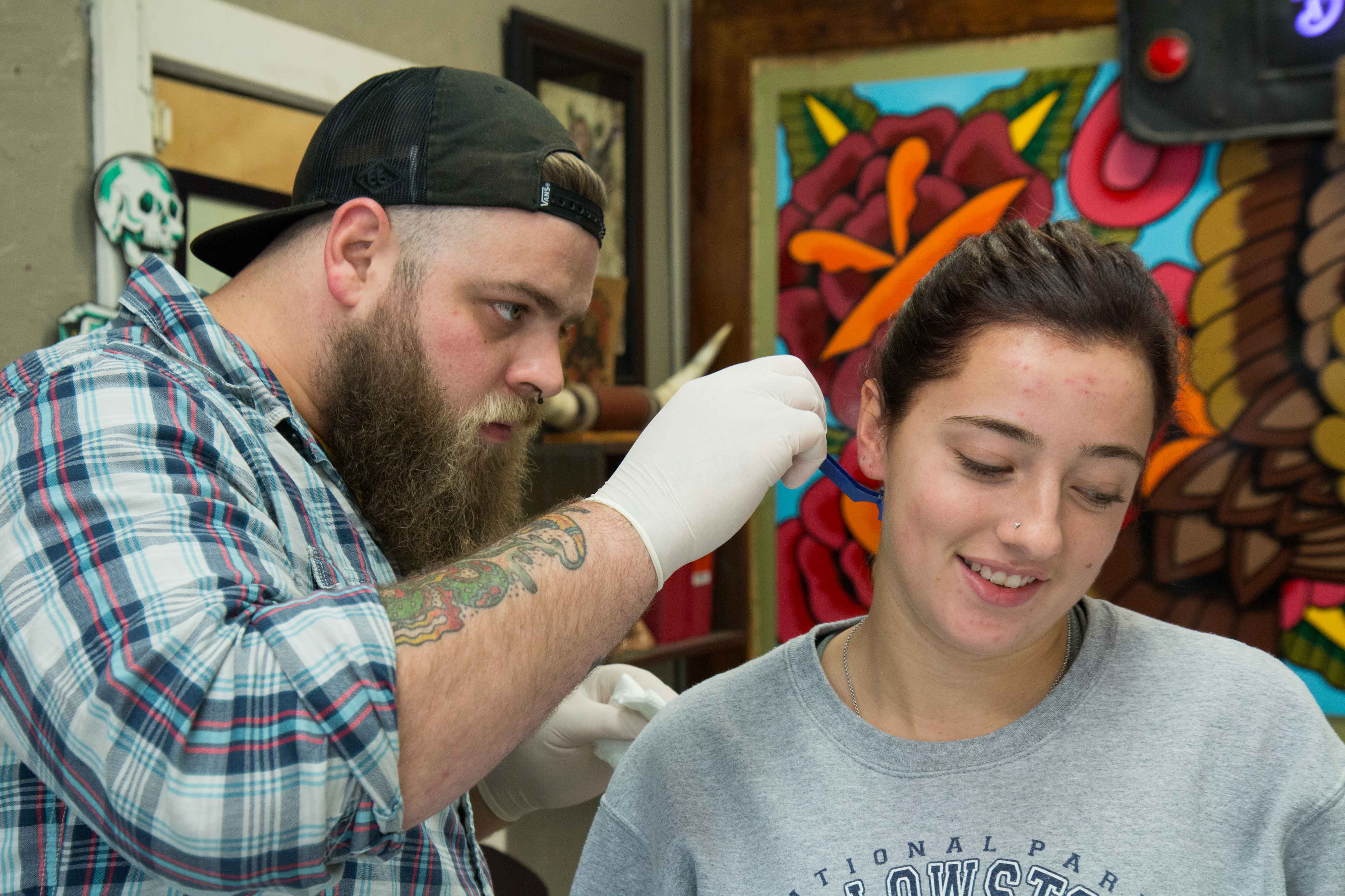 tattoo artist Austin Liebst shaves the area where Emma Hickey will be getting her second tattoo, at Artist at Large. Hickey's first tattoo is on her wrist and it's her mother's handwriting with the message: