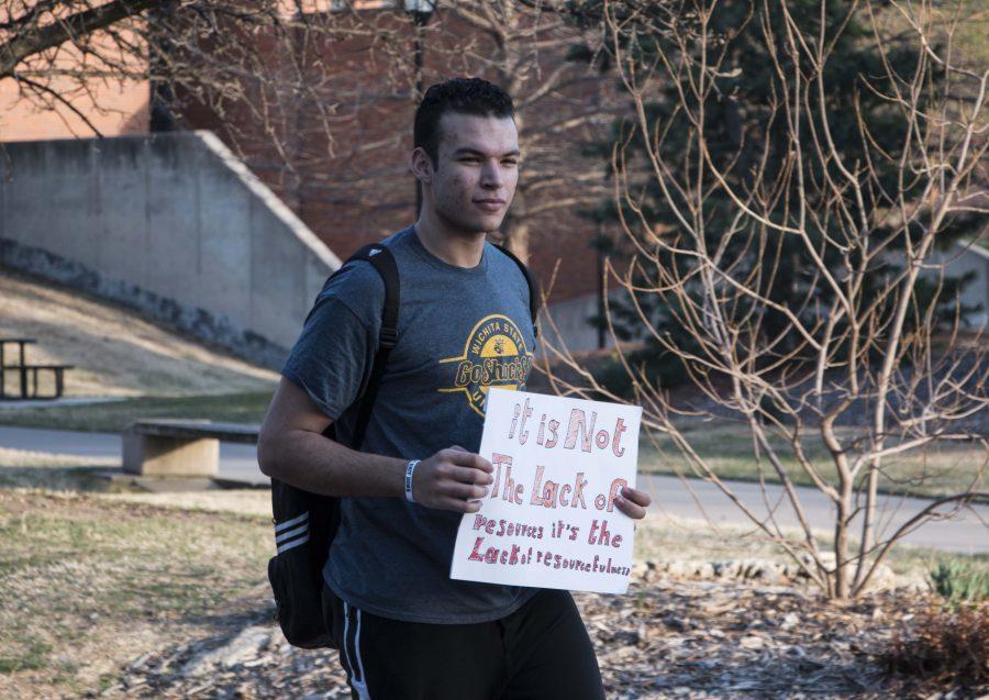 Amr Wahba, a protester, holds a sign in opposition to the construction of a YMCA facility on Wichita States campus. The proposal calls for a student fee of $7.75 per credit hour to be added to financially support the facility. 