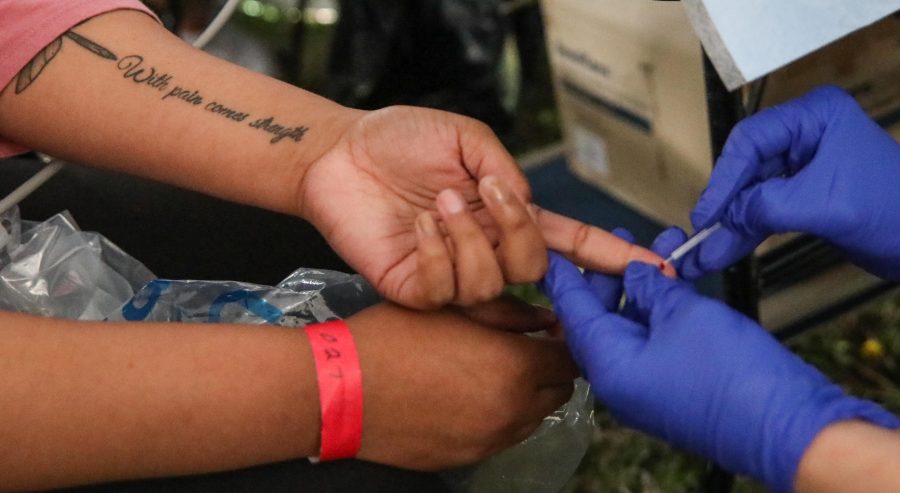 A volunteer draws blood from Kaesha Malcolm, 19, during Saturday’s day of free health care in Fairmount Park. Malcom, who suffers from hypothyroidism, has a tattoo that reads with pain comes strength.