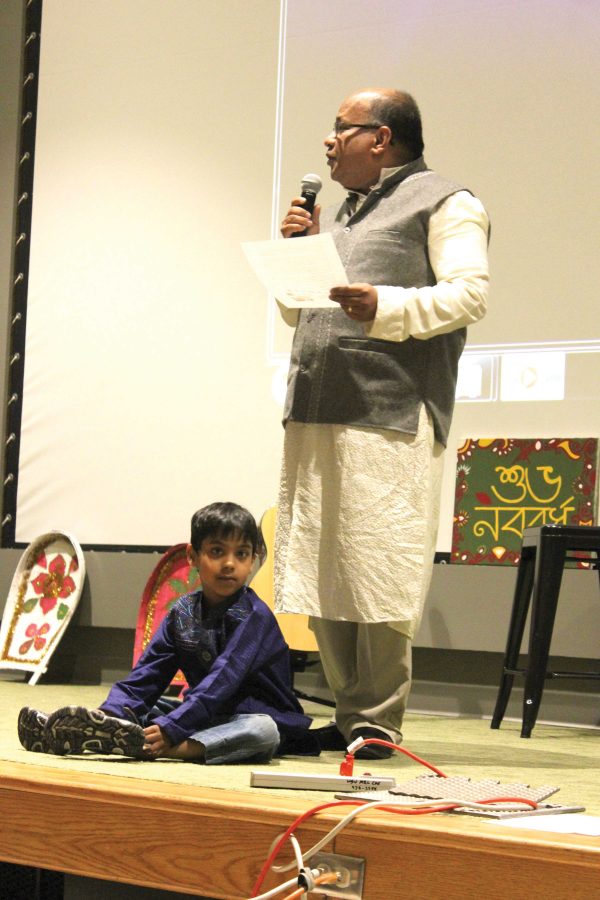 Dr. Anwar Chowdhury gives a speech while his son Rihan sits at his feet during the Bengali New Year event in Hubbard Hall.
