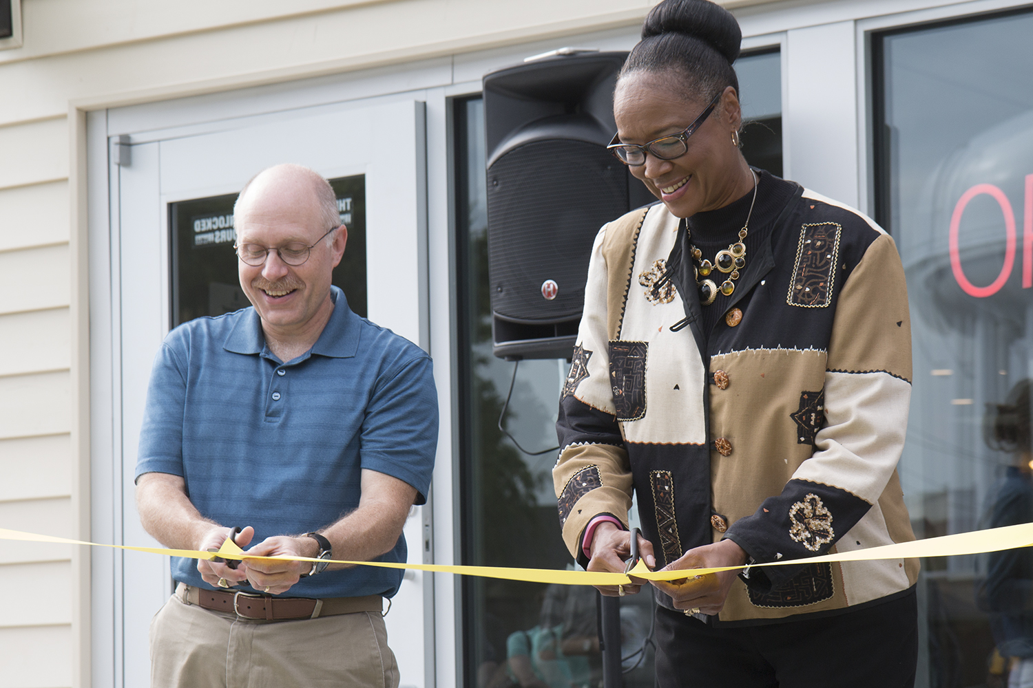 Toby Ortstaft, Board President of the Lutheran Student Center, left, and Lavonta Williams, a member of the City Council for District One, right, prepare to cut the ceremonial ribbon for the grand opening of Fairmount Coffee Co. 