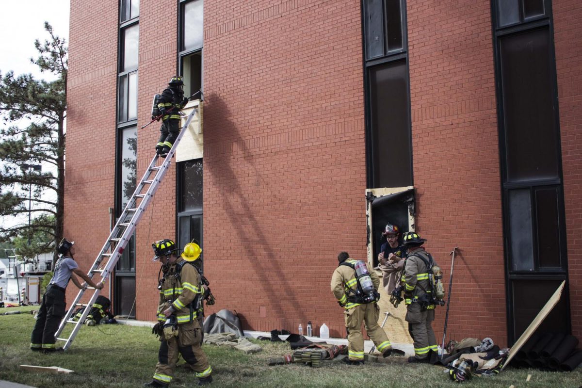 Firefighters using ladders to rescue victims from upper level floors.