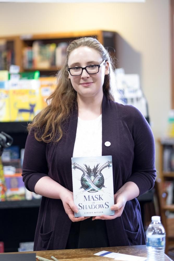 Linsey Miller holds a copy of her debut novel, Mask of Shadows.