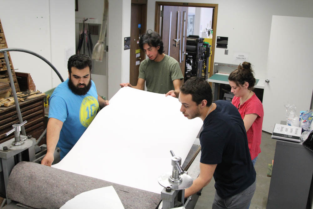 Students help teacher, Marco Hernandez, place printing paper on Sept. 27. The students had to be careful and precise to place the paper in the correct position.