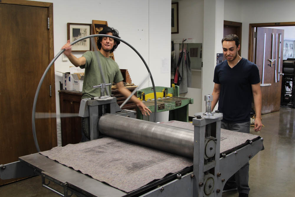 Andres Levaggi Villanueva assists teacher Marco Hernandez by rolling his print for him on Sept. 27. Andres got to learn how to use this print making by assisting his teacher. The print had to be rolled through twice to be properly done.