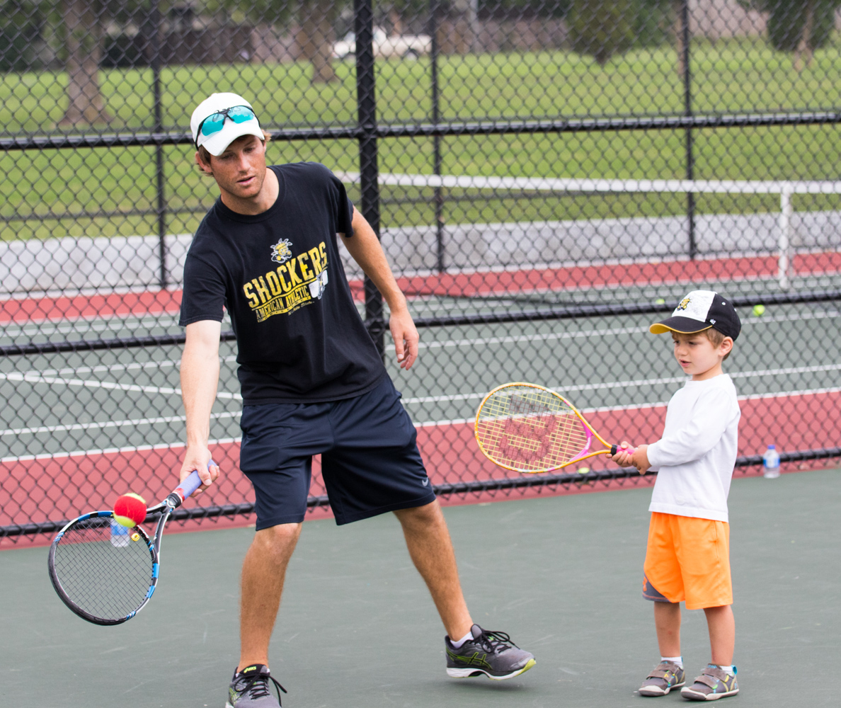 Coach Colin Foster plays tennis with a youth at the free clinic. (File photo)