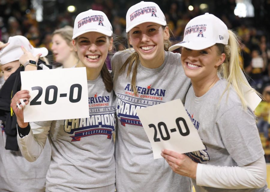 Seniors Mikaela Raudsepp, Abbie Lehman, Emily Hiebert pose with their 20-1 sign after sweeping the American Conference. (Nov. 24, 2017)