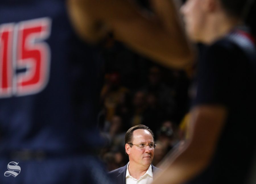 Two Newman players frame Wichita State Shockers head coach Gregg Marshall during the charity exhibition game in Koch Arena.