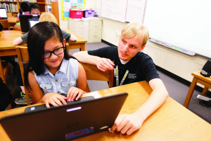 Zane Storlie, a junior computer science major, helps an elementary school student during a Scratch lesson.