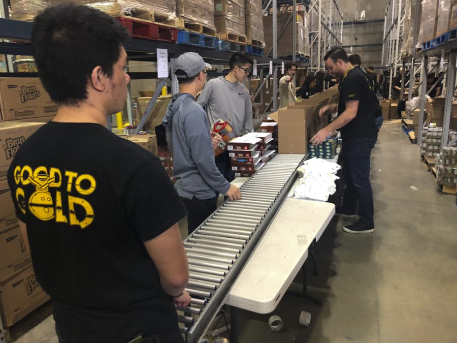 Cortez Schenck and teammates package food boxes at the Kansas Food Bank. The boxes include shelf-stable healthy food options.