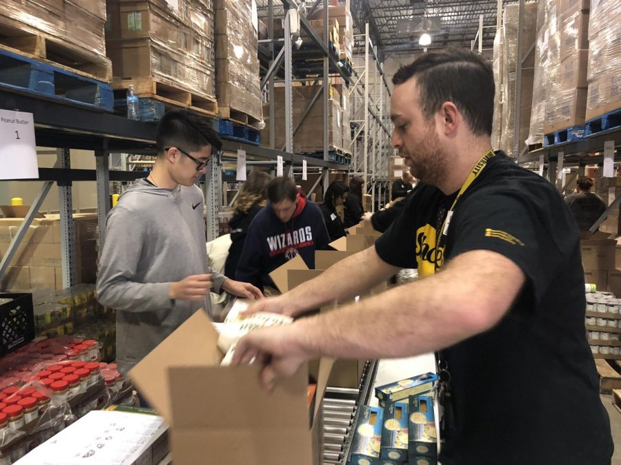 Cortez Schenck (left) and teammates package food boxes at the Kansas Food Bank. The boxes include shelf-stable healthy food options.