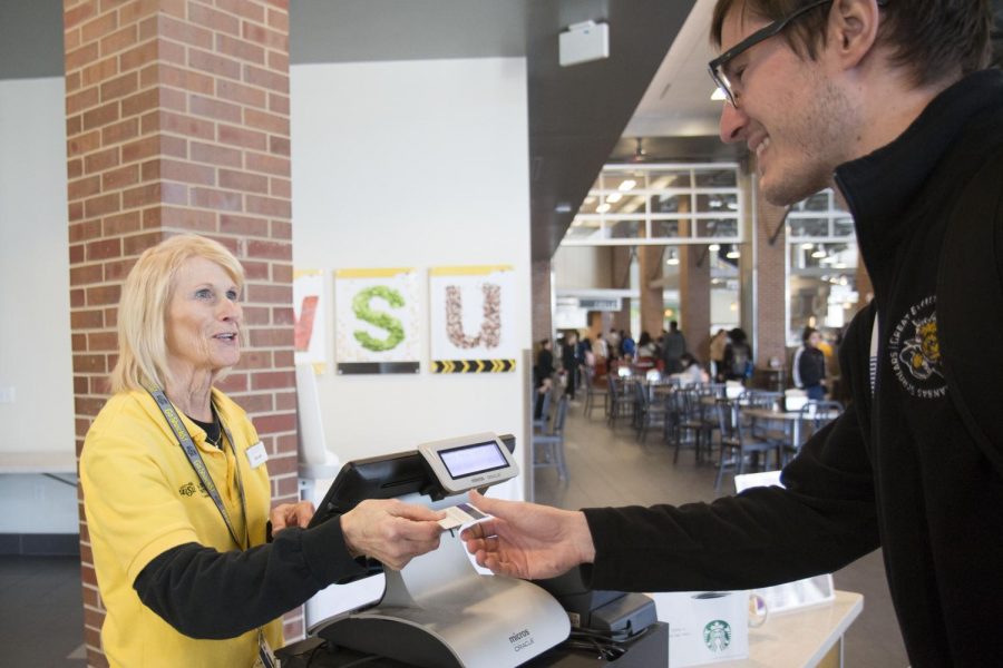 Cashier Maureen Coleman swipes a student's meal card in the Shocker Dining Hall. 