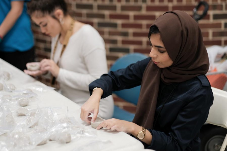 A junior majoring in Biomedical Engineering, Jana Alnasser, builds a pinch pot out of a piece of clay.