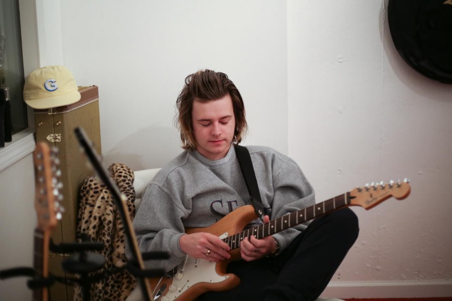 Oliver Milmine, who performs under the name Tommy Newport, plays guitar in his home studio.