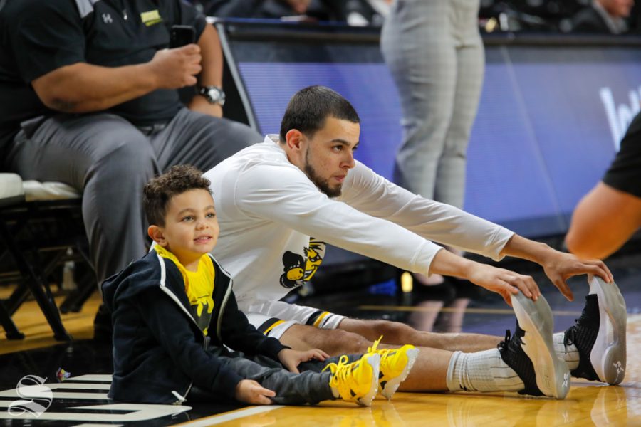 November 7, 2018: Adriel, 4, stretches with his dad before the game on Nov. 6, 2018. Adriel is the son of Wichita State guard Ricky Torres.