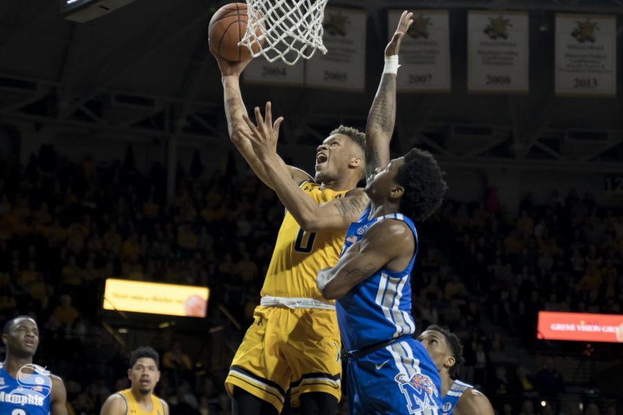 Wichita States Dexter Dennis splits the defense and finishes at the rim during the game on Feb. 23 at Charles Koch Arena.