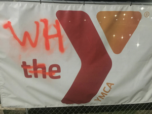 Signs hanging on the fence around the YMCA construction site were vandalized Thursday.