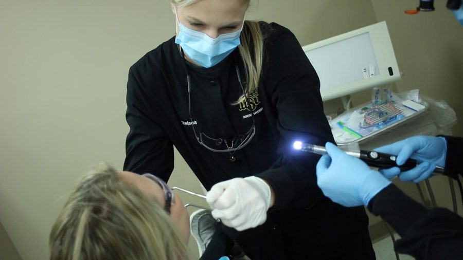 Wichita+State+dental+hygiene+student+Allyssa+Kirkham+examines+her+sisters+teeth.