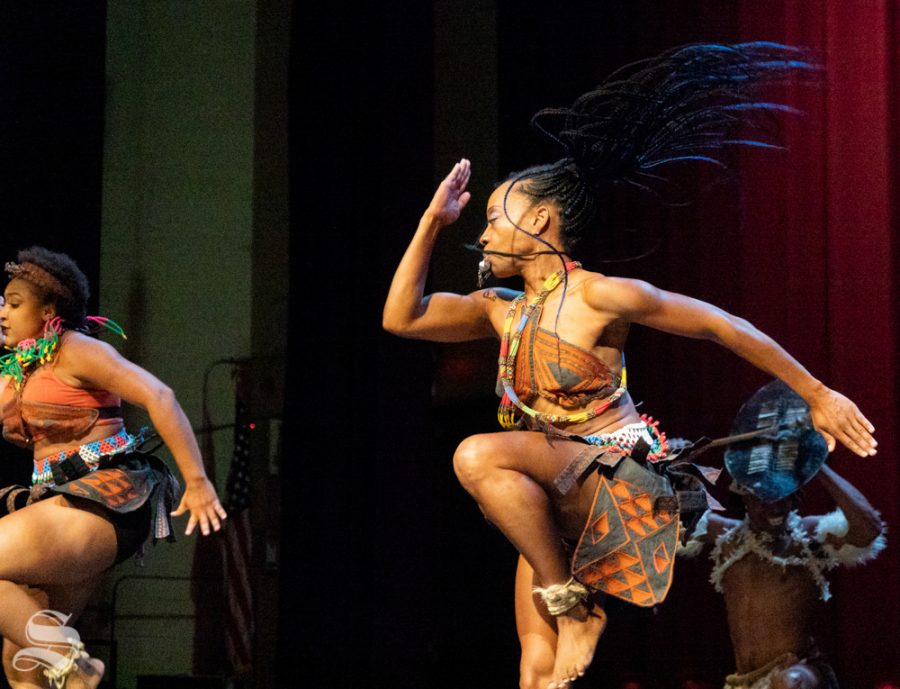 Members of Step Afrika! strike their hands mid-air during a step routine.
