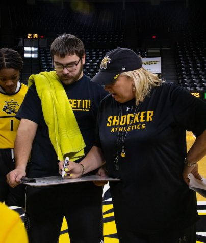 Neil Terry, a manager for the Wichita State women's basketball team, holds a white board for Head Coach Keitha Adams as she draws up a play during practice. Terry's late mother was high school best friends with Adams.