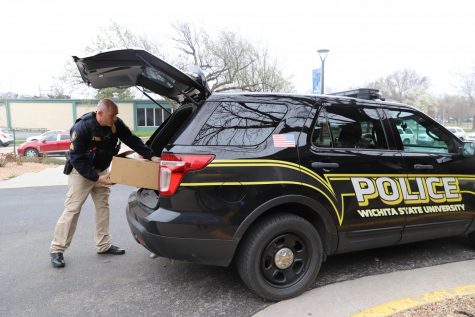 Wichita State Police Sergeant Christopher Tenet unloads a box of personal protective equipment from his police vehicle. Tenet made a delivery to the University of Kansas Medical Center on March 27, 2020.