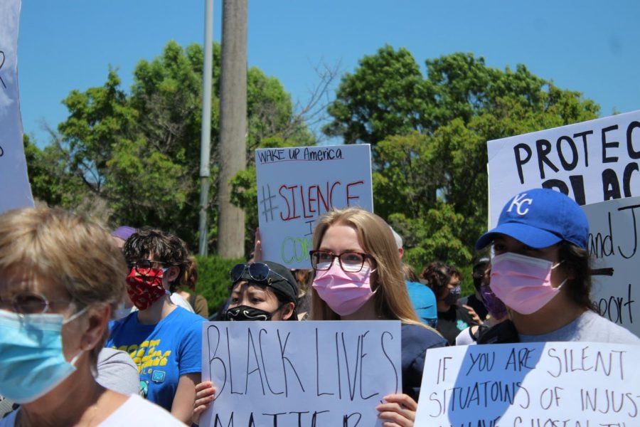 A crowd of protesters, including recent WSU graduate Alec Tucker (center), hold signs on Saturday during a protest outside of a Wichita police station near campus.