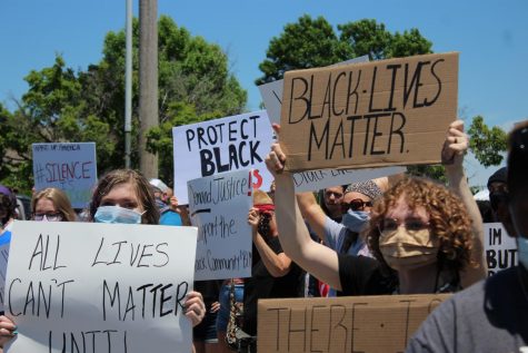 Demonstrators hold signs on Saturday during a protest against police brutality near Wichita State's main campus.