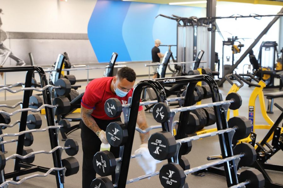 Jack Tomlinson, an employee at the Steve Clark YMCA, wipes down a piece of workout equipment on Friday. The Y reopened last week.