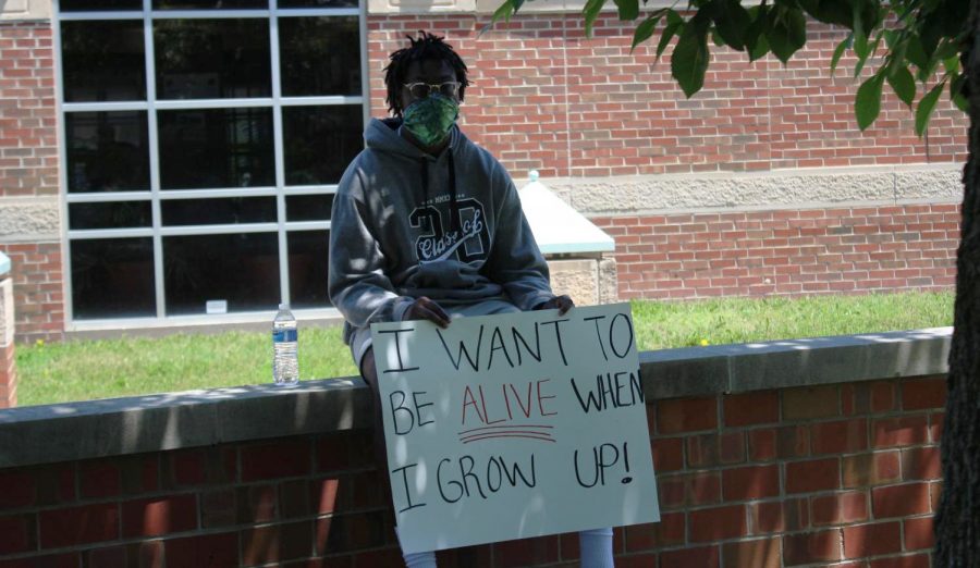 A demonstrator holds a sign during a protest on Saturday outside of the Wichita police station near WSU.