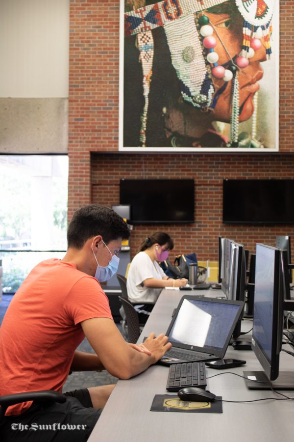 Senior, Elio Lago is using his laptop at the Ablah Library while practicing social distancing. Certain computers in the library have signage that prohibits students from working side by side with each other. 