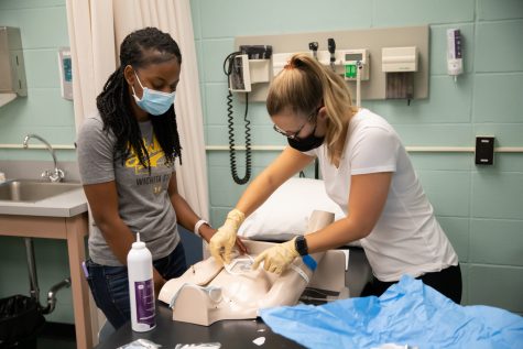 A Wichita State nursing student practices a demonstration by cleaning and bandaging a mannequin on Thursday inside Ahlberg Hall. These life-like mannequins help nursing students to picture what their future careers might look like.