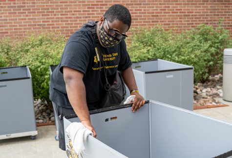 Omar Brantley, a volunteer at Shocker Hall, wipes down carts used to transport residents' belongings on Monday afternoon. More than 1,000 students are moving into residence halls this month.