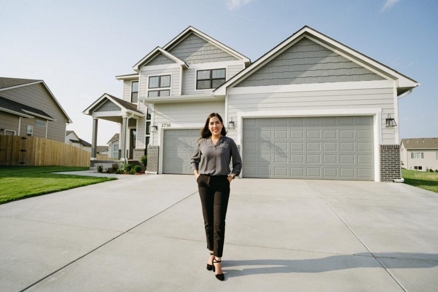 Wichita State senior Jennifer Castro poses in front of a listing from Miller Family Homes. Castro is a licensed real estate agent, and has been interning with the real estate firm since graduating high school.