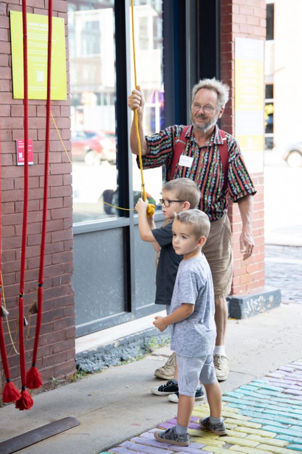 Mike Miller creator of the Rythm Maker! shows two boys how the art work operates at Gallery Alley on July 2, 2021.
