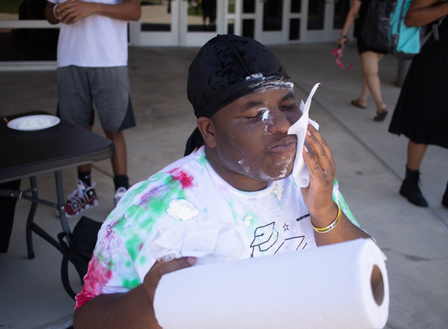 President of Wichita States Black Student Union, Omarian Brantley cleans off the whip cream off his face after getting pied mutliple times on Aug. 23.