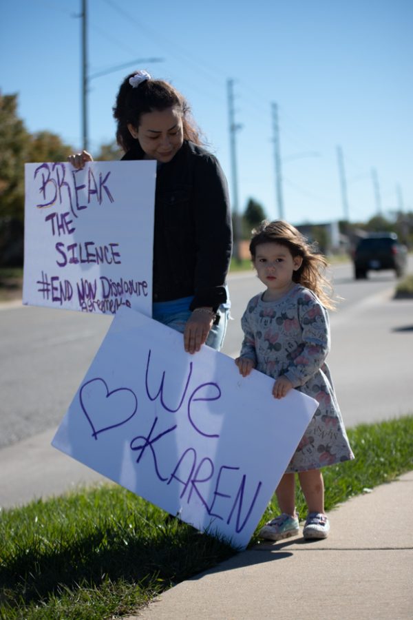Kristen Gowell and her daughter hold signs to help support Karen Countryman-Roswurm outside of the Metroplex on Oct. 29. Gowell and her children stood outside of the 2909 Oliver apartments on the sidewalk.