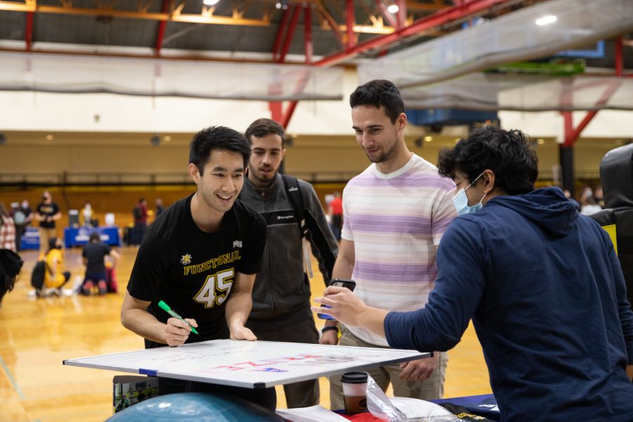 Shocker Fit Instructor Tristram Nguyen signs students up for a game. Shocker Fit offered free health classes for students to take in the Heskett Center.