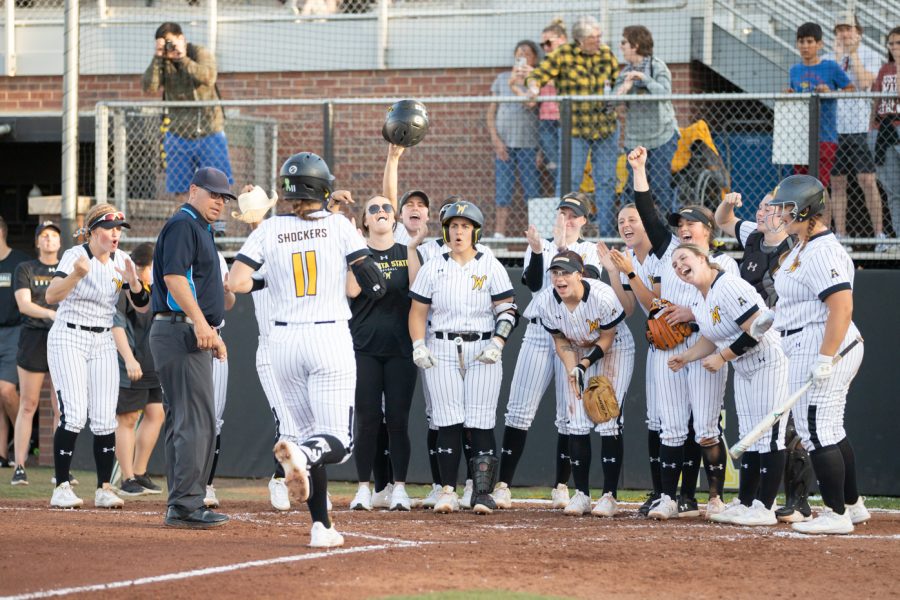 Senior Neleigh Herring runs to home plate to be greeted by the Shocker softball team during the game against KU on April 20.
