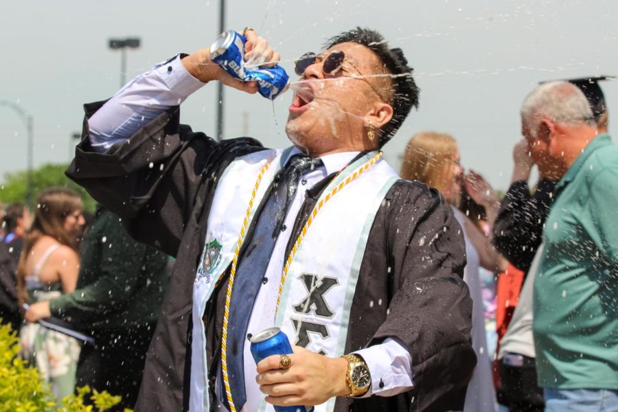 Spring 2022 graduate celebrates by smashing two Bud Light cans together and drinks them after the Spring Commencement Ceremony on May 14.