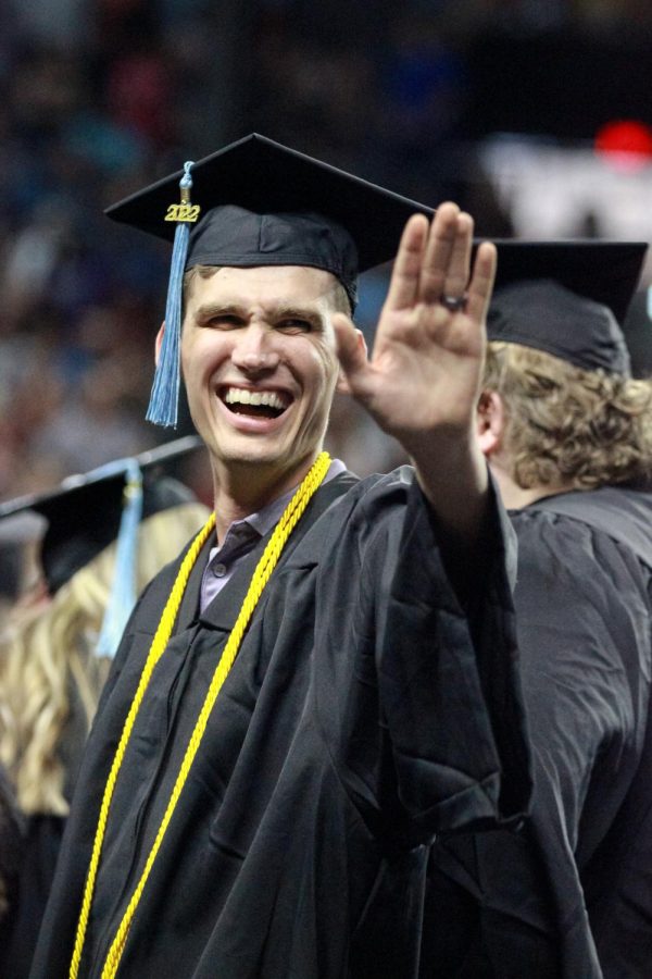 Graduate waves to family and friends in the crowd at Charles Koch Arena on May 14, 2022