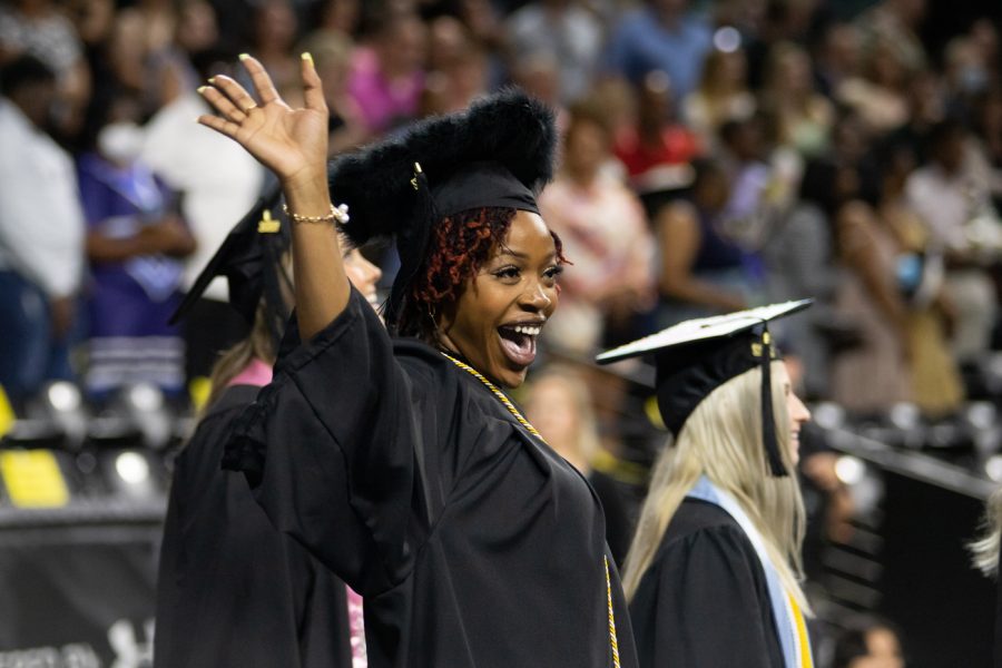A graduate waves to family and friends before the first ceremony begins on May 14. The first ceremony was for all graduates somewhere in the Fairmount College of Liberal Arts and Sciences, College of Fine Arts, Dorothy & Bill Cohen Honors College or College of Innovation and Design.