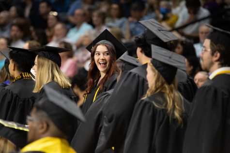 Graduate Kayla Knoll smiles at her fellow graduates while waiting to walk across the stage to receive a diploma.