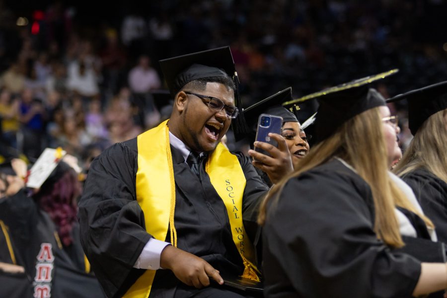 A graduate takes a picture after receiving their degree on May 14.